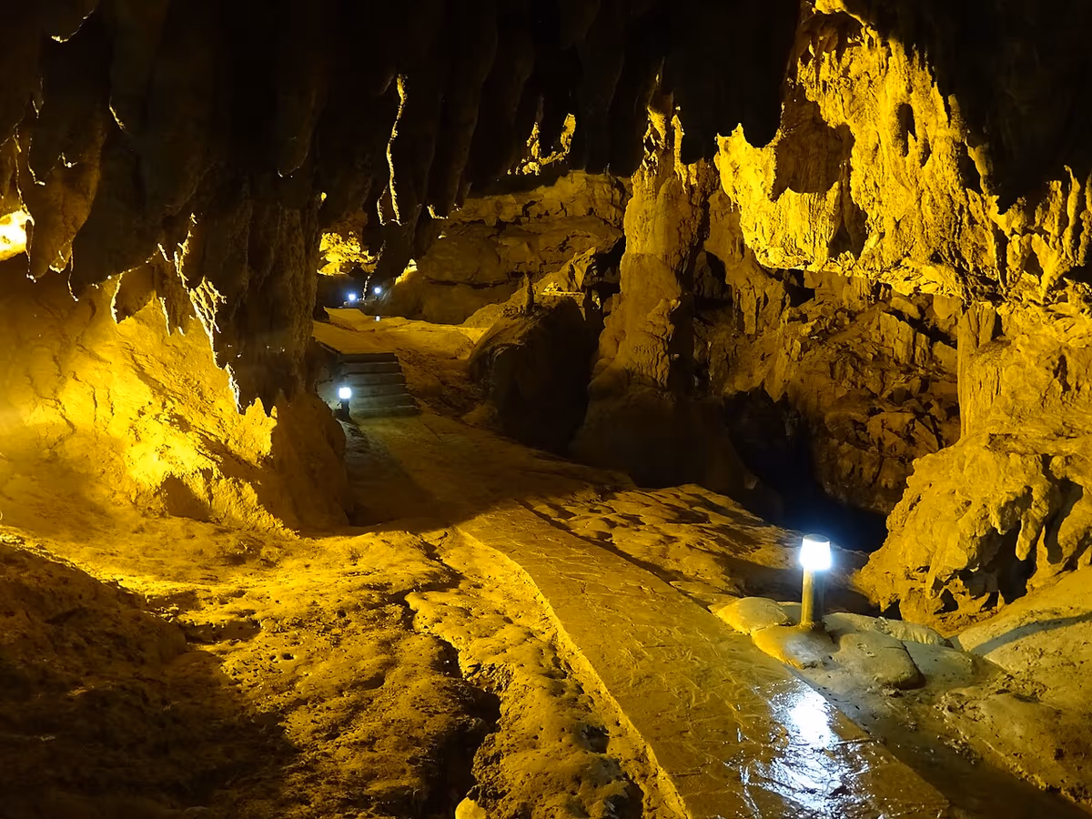 A lit concrete walkway winding between stalactites and rock walls inside Nguom Ngao Cave
