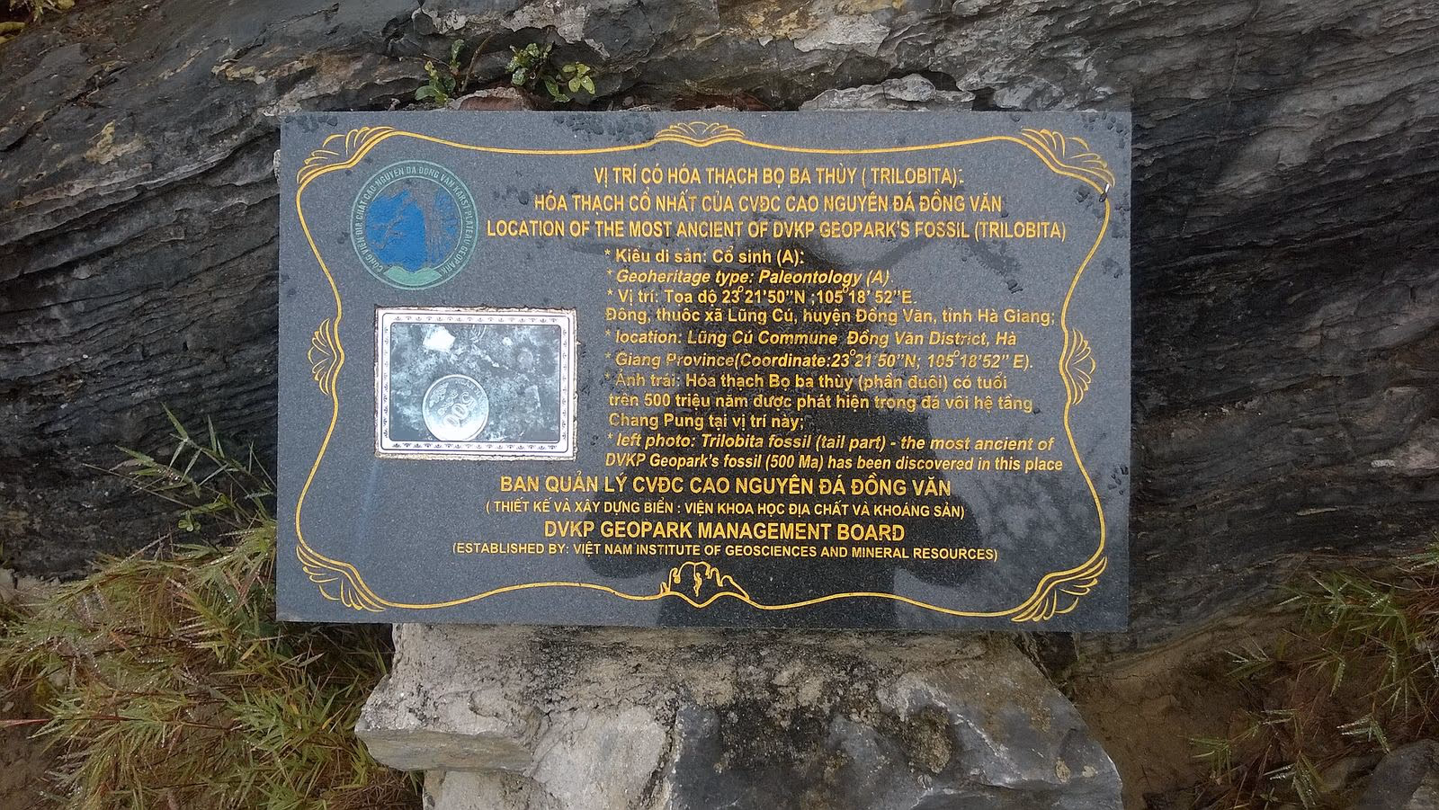 Geopark information plaque marking the trilobite fossil site at Lung Cu, with a photo of the fossil next to a coin
