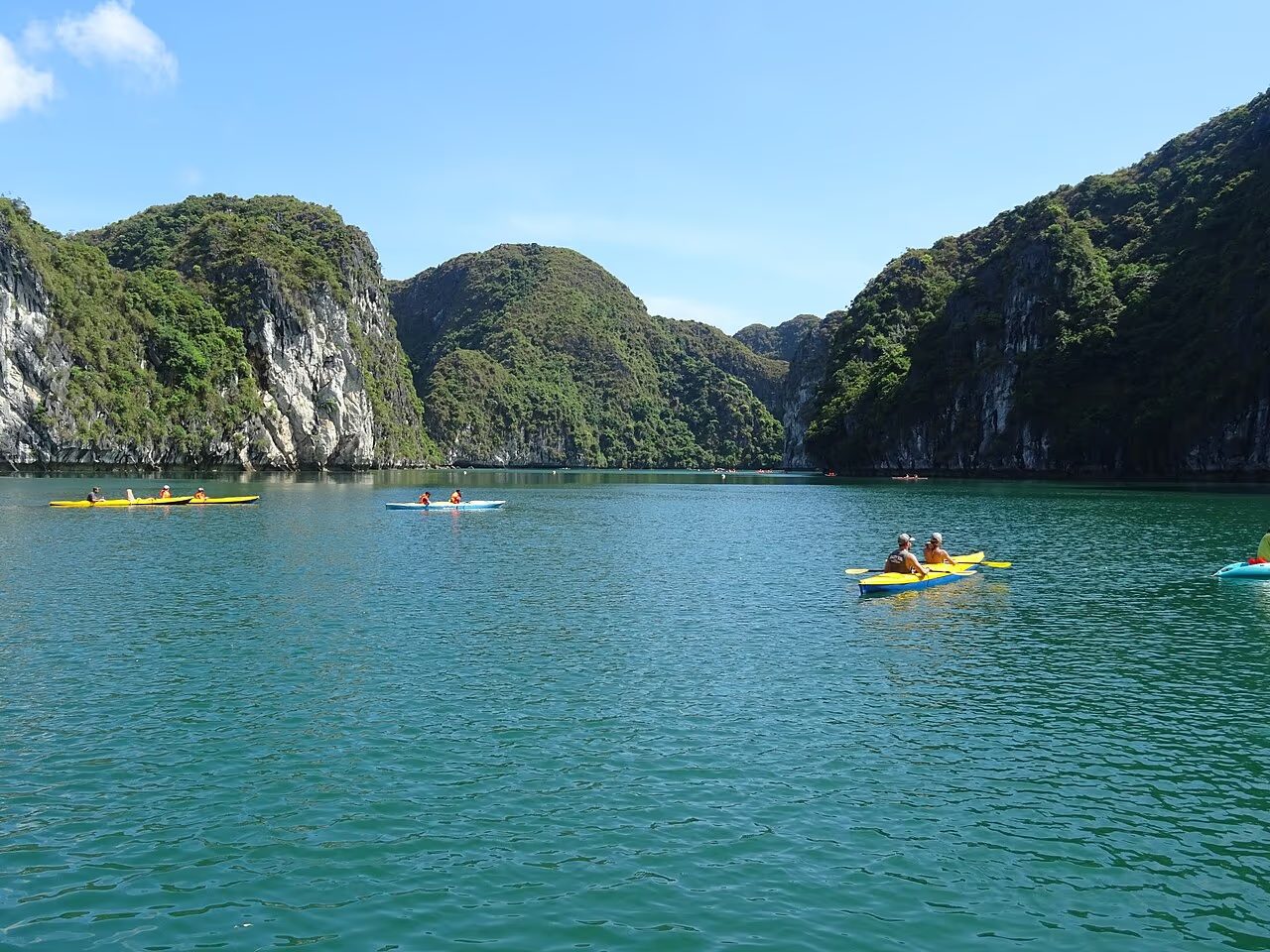 Tourists kayaking on the emerald water of Ha Long Bay between limestone karst islands in Vietnam