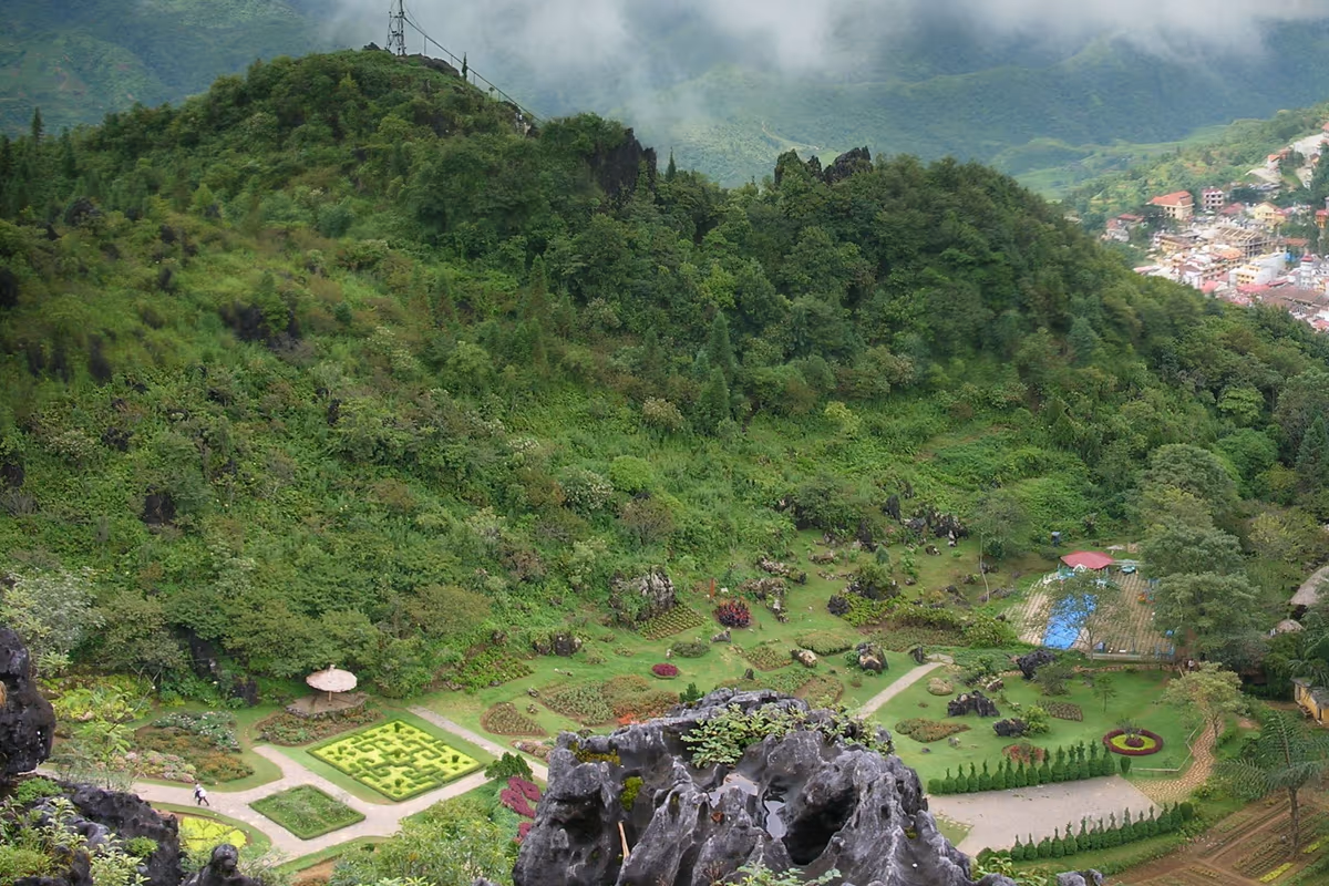 Hedge-maze flower garden and karst stone forest rocks inside Ham Rong Mountain, with Sapa town visible below