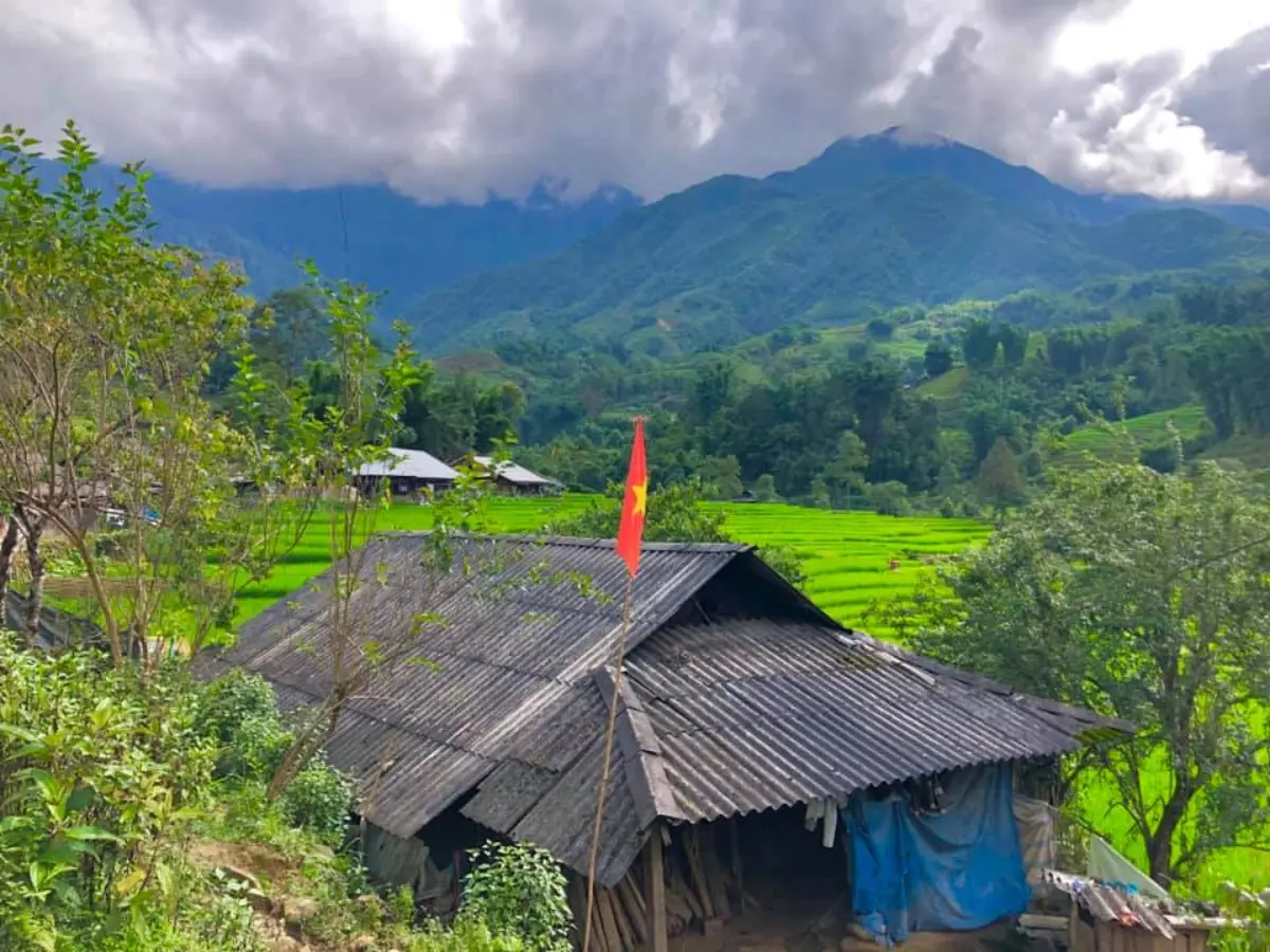 Black H'mong village house with Vietnam flag and rice terraces — Sapa, Lao Cai, Vietnam