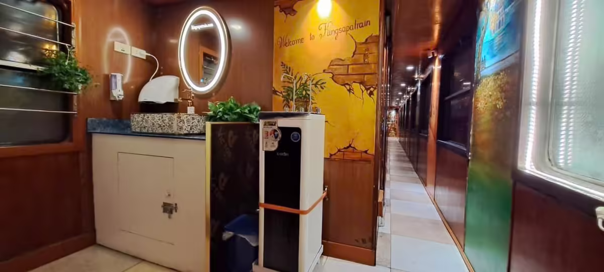 Inside a King Sapa Train carriage — the corridor with a lit mirror, washbasin, water dispenser and a Welcome to Vietnam mural