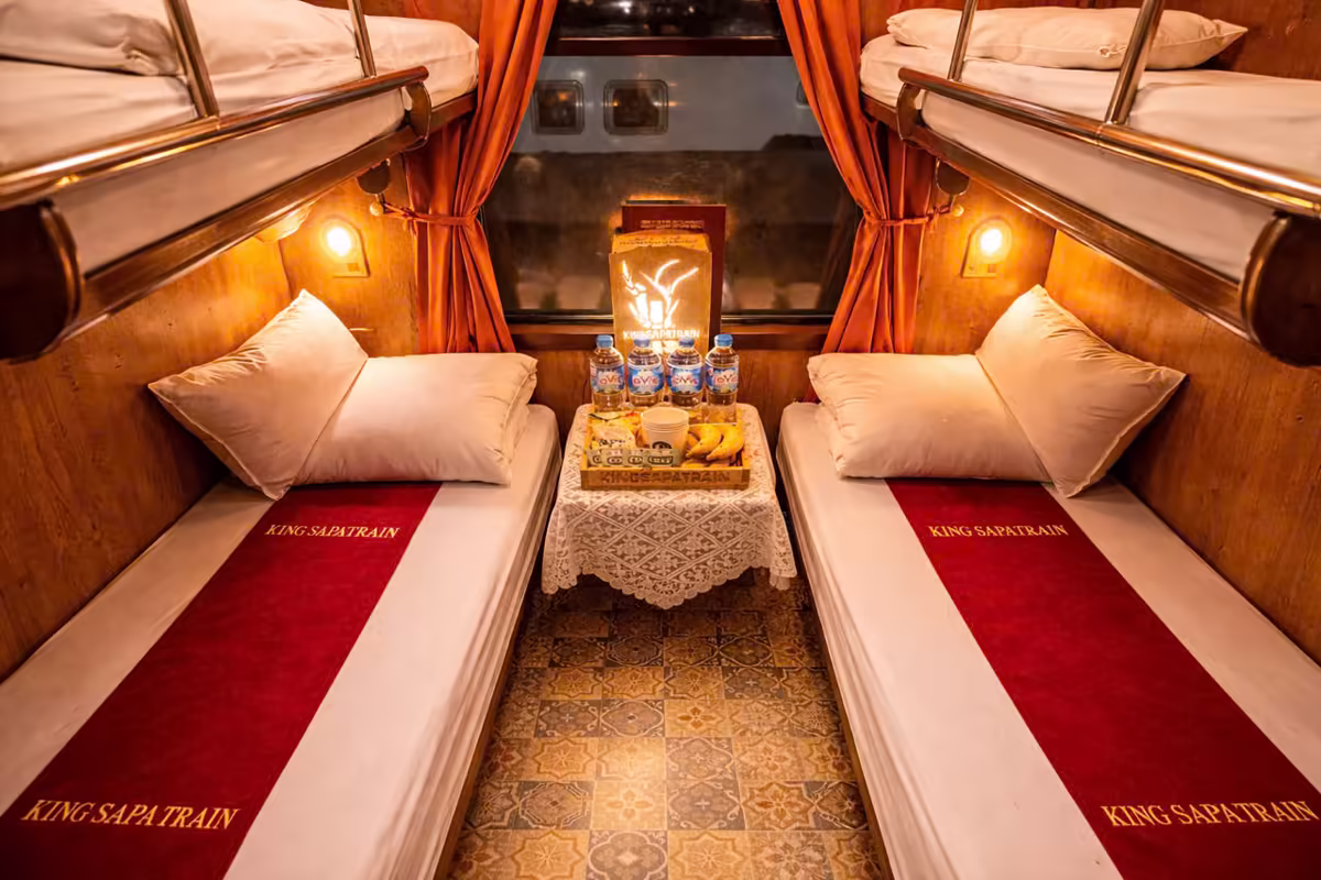 King Sapa Train 4-Berth Suite cabin with embroidered red bed runners, welcome fruit tray and tiled floor