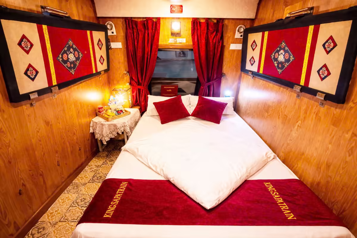 King Sapa Train Private VIP Double cabin with one double bed, red cushions and embroidered wall panels