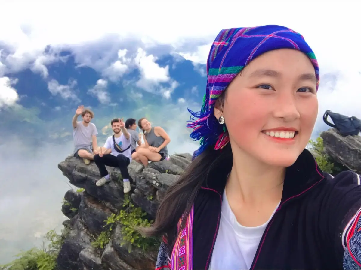 Travelers at a rocky mountain viewpoint above the clouds in northern Vietnam with a local guide