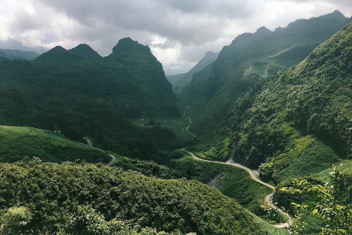 Winding road through a narrow green karst valley with towering limestone mountains on both sides in northern Vietnam