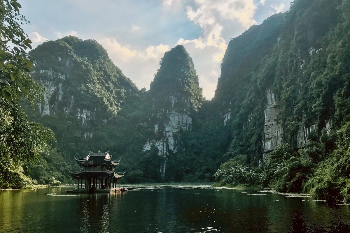 Traditional Vietnamese pavilion on the river at Trang An surrounded by towering karst limestone cliffs