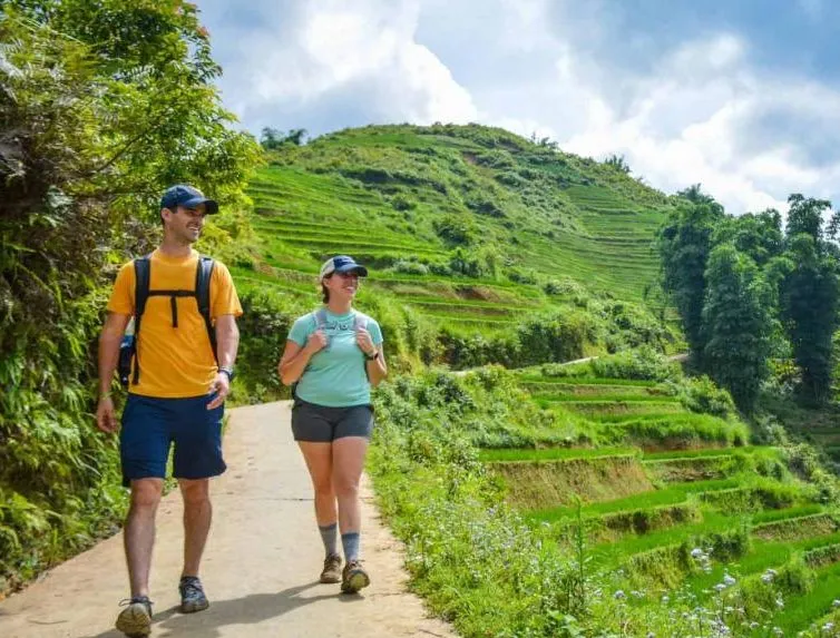 Trekking through Sapa rice terraces — couple on the trail to Lao Chai village