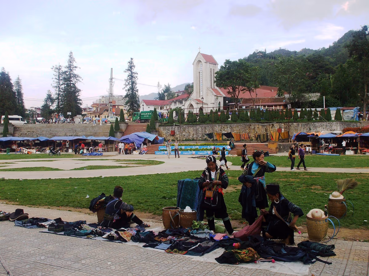 H'mong women selling embroidered cloth on the paved square in front of the Sapa Stone Church