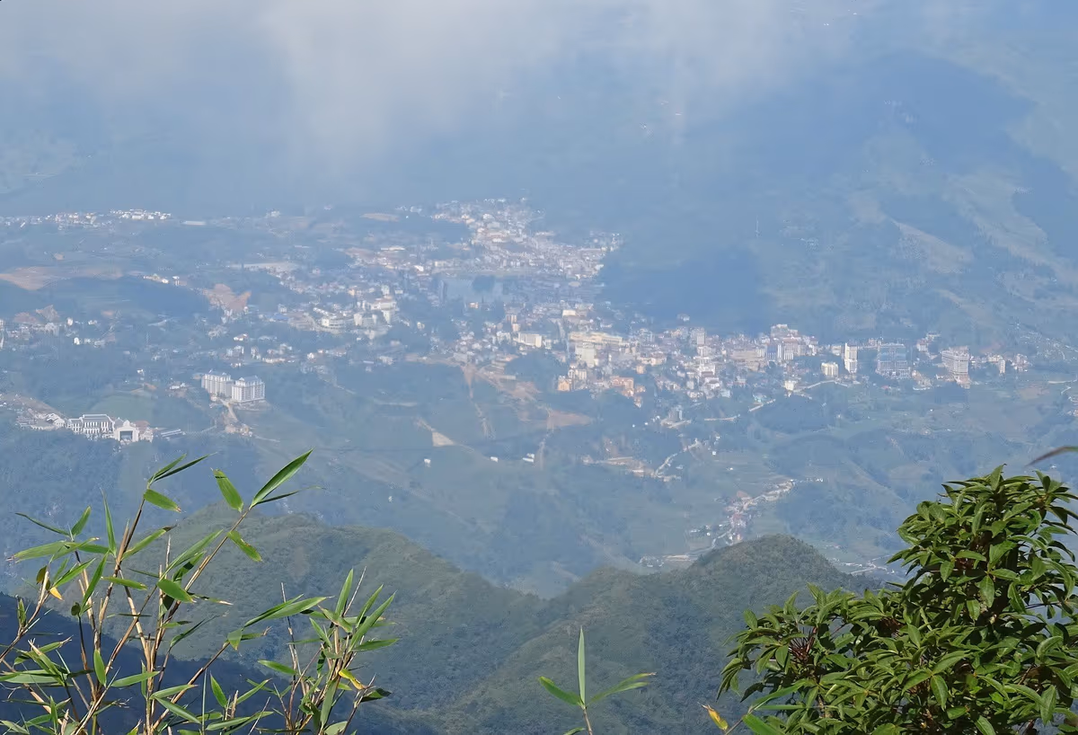 Sapa town spread across a hillside far below, seen from the Hoang Lien Son mountains