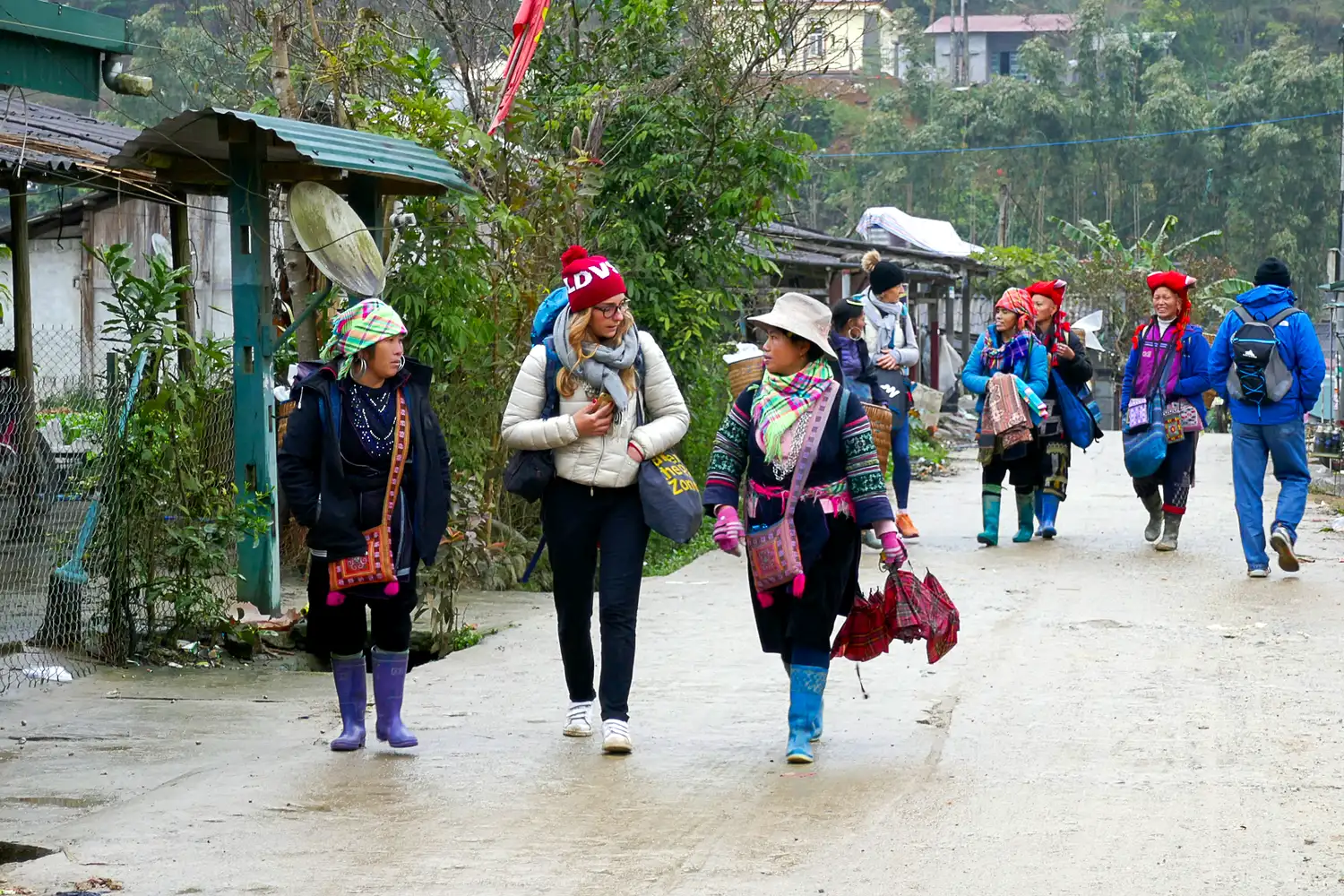 Travellers trekking with local Black H'mong guides through a village near Sapa in northern Vietnam