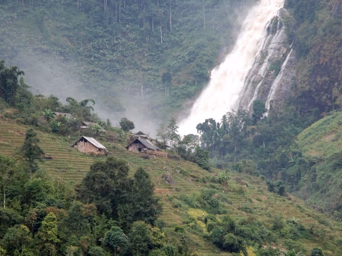Silver Waterfall dropping past a Hmong hillside hamlet and terraced fields on the O Quy Ho Pass road, Sapa