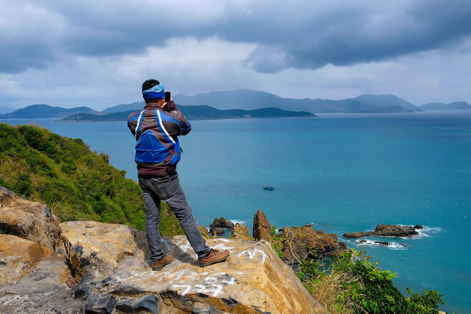 A solo traveller standing alone on a coastal headland in Vietnam, looking out over the sea