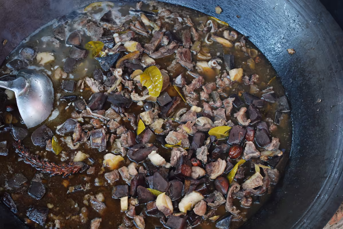 A large cauldron of thang co, the traditional Black H'mong stew, simmering at a Sapa-region market