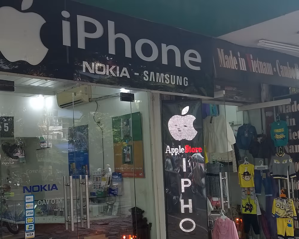 The glass front of a phone shop in Hanoi with iPhone, Nokia and Samsung signs and a Vietnamese flag